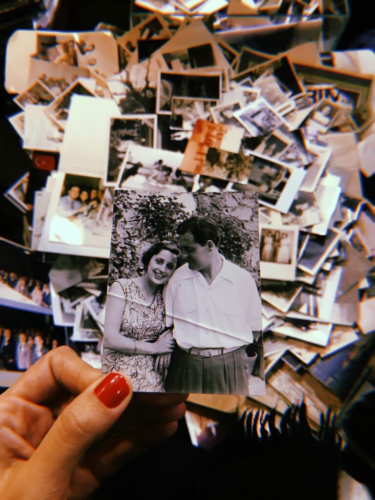Hand holding a vintage couple photo over a pile of nostalgic photographs.