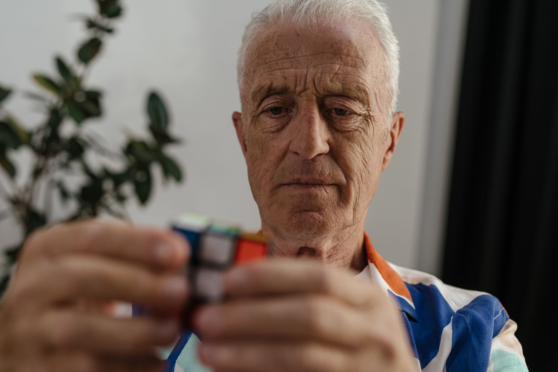 pexels photo 8900003 8900003 Elderly man concentrating on solving a Rubik's Cube, showcasing focus and mental agility.